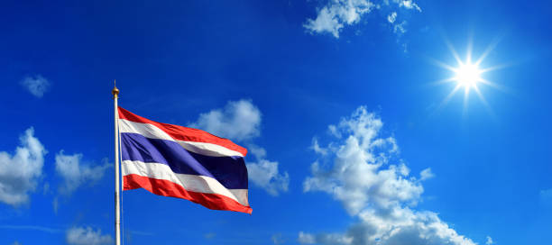 Thai flag at flagpole over sunny blue sky stock photo