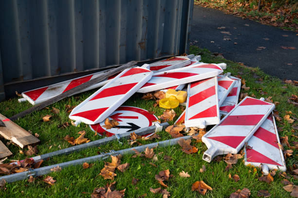 Mobile red and white plastic barriers and traffic sign lie on the grass. Close-up.