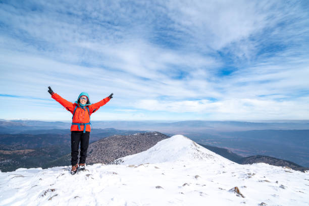 istock Female mountain climber leader  is making peace sign and celebrating her success while watching  the beautiful scenery of forest  and mountain range on the summit of a mountain 1445823237