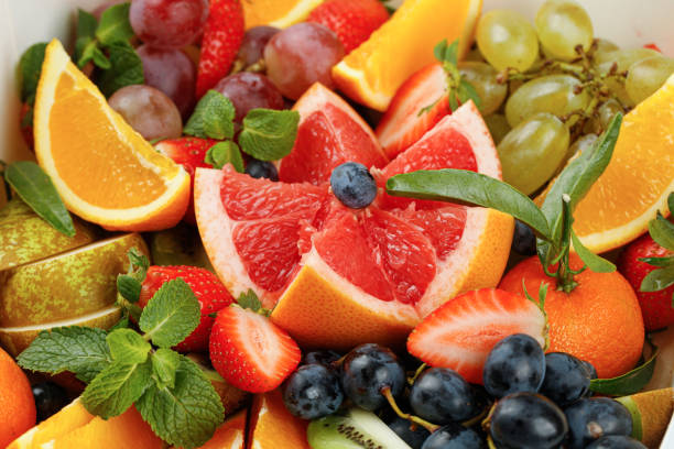 istock Background with different chopped fruits, grapefruit, grapes, kiwi, pear, strawberry, tangerines. Fruit basket close up. 1445824090