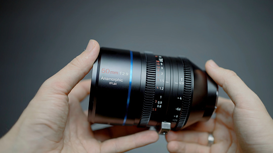 China, Beijing - March 5, 2022: New lens for professional shooting. Action. New anamorphic lens for full-scale shooting and cinematic effect. New generation lens in hands of professional photographer.