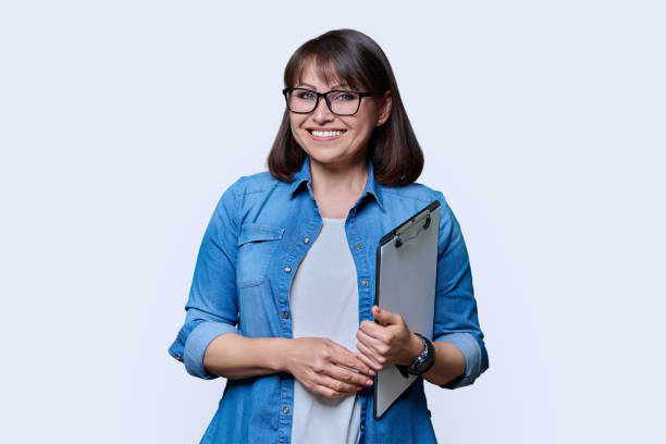 donna di mezza età con gli appunti che guarda la macchina fotografica su priorità bassa bianca - businesswoman form finance women foto e immagini stock