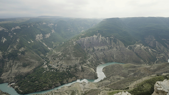 Bottom view of mountains and waterfall through the smartphone camera. Action. Close up of hand holding a tripod with fixed camera and shooting wild natural landscape