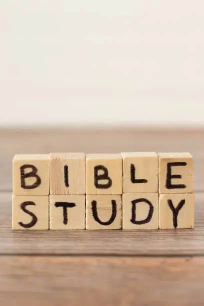 Bible study handwritten text on wood cubes on rustic table with white background. Copy space. Vertical shot, a closeup.