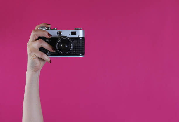 istock retro camera in a female hand on a pink background 1445830405