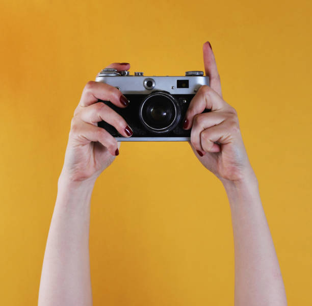 istock retro camera in female hands on yellow background 1445830407