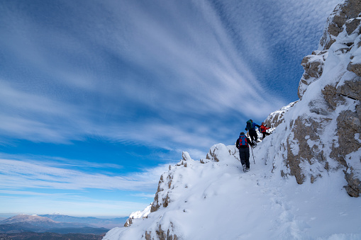 Alpinist climbers are enjoying the climb while standing on snowy mountain crest on extreme harsh conditions.