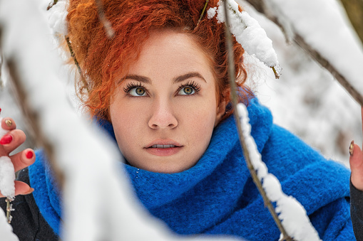 Portrait of beautiful young woman with scarf enjoying in winter forest