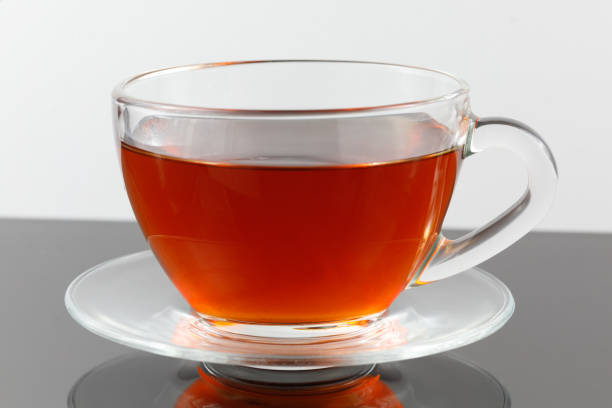 Black tea in a cup on a gray background.