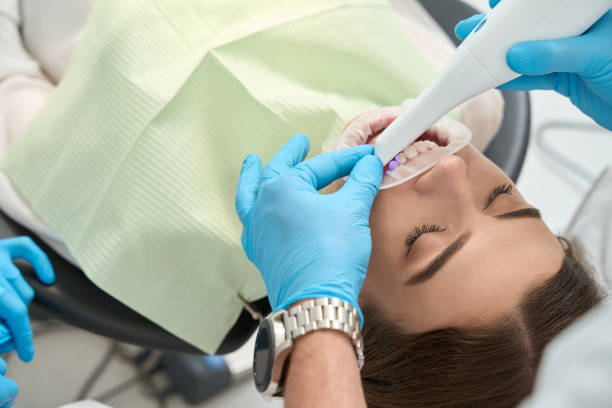 Stomatologist examining female client mouth with intraoral scanner stock photo