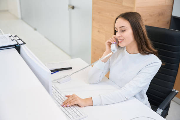 istock Cheerful secretary talking on telephone at reception desk 1445836489