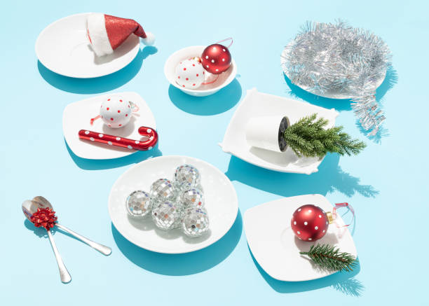 istock Christmas table surreal composition made with Christmas decorations on white plates and spoons on bright blue background. New Year or Xmas concept. Creative holiday dinner party abstract idea. 1445836619