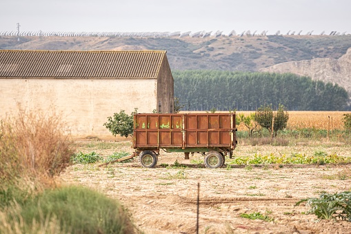 istock Rural image of a tractor trailer used in agriculture parked in a farm field near a shed 1445838623