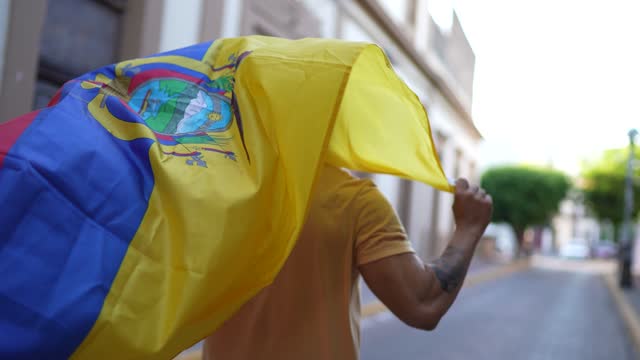 Mature man running while holding a ecuadorean flag in the street