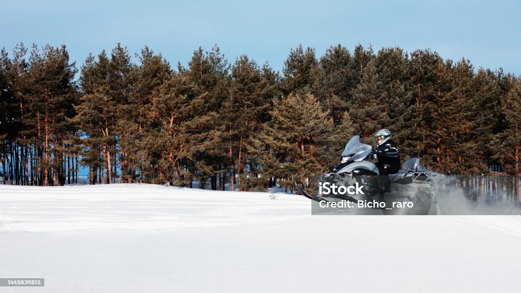 In deep powder snowdrift snowmobile rider driving fast. In deep snowdrift snowmobile rider driving fast. Riding with fun in white snow powder during backcountry tour. Extreme sport adventure, outdoor activity during winter holiday on ski mountain resort. Snowmobiling Stock Photo