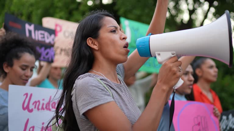 Young protester woman leading a demonstration using a megaphone outdoors