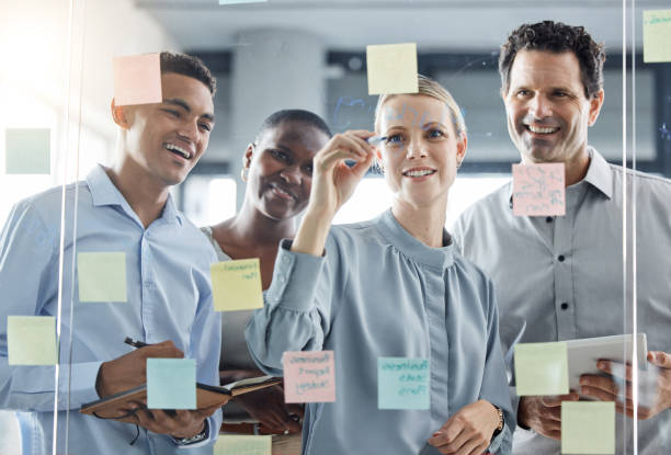 istock Glass, wall and sticky notes with business people collaboration, planning and schedule management in office. Innovation, thinking and team strategy for goal and vision mission by working entrepreneur 1445841368