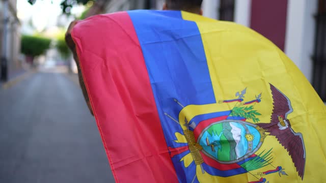 Mature man running while holding a ecuadorean flag in the street