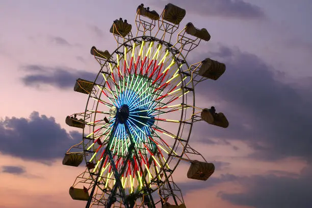 People riding on a ferris wheel with late evening sunset and clouds