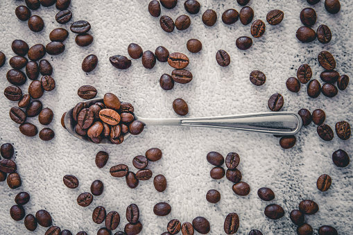 A steel spoon on a background of scattered coffee beans