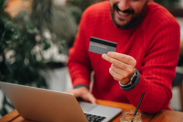 Close up of a man holding a credit card, online shopping on a laptop stock photo