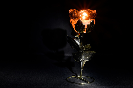 candlestick in the form of a flower with a candle in the dark on a black background