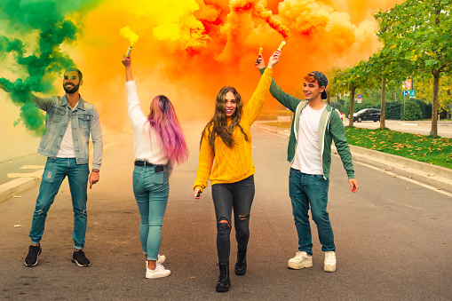 multi-ethnic teenage ersasmus student group celebrates with smoke bomb. 
concept about freedom and happiness
