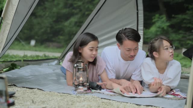 Two teenage girls and their father lie down in a tent and try a riddle.