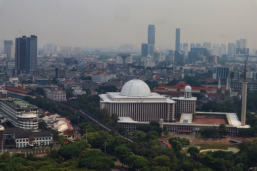 The Istiqlal Mosque stands firmly in white in the middle of the city of Jakarta