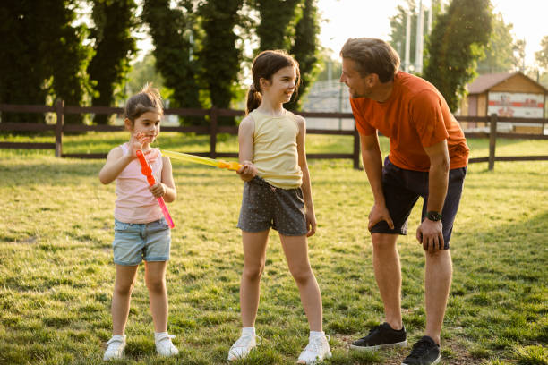 istock Two sisters playing with bubbles and enjoying a picnic with their dad 1445857394