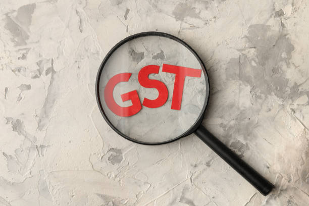istock The word GST under a magnifying glass on a light concrete background. view from above 1445858561