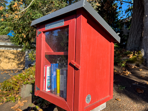 Seattle, WA USA - circa November 2022: Close up view of a red Little Free Library in a residential neighborhood.