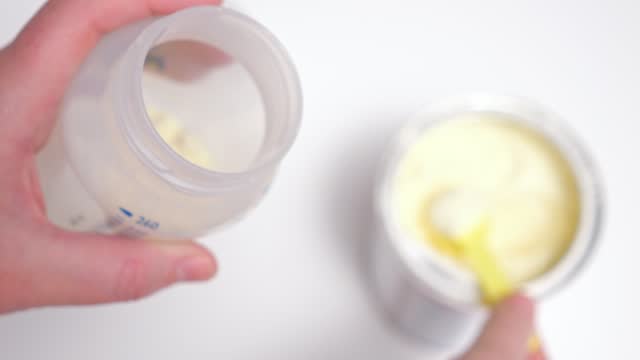 Parent takes scoop of powder for making food fusion for baby