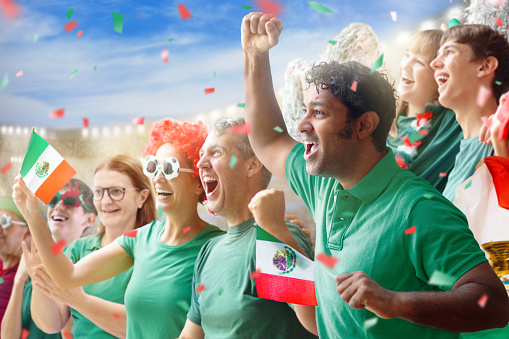 Mexico football supporter on stadium. Mexican fans on soccer pitch watching team play. Group of supporters with flag and national jersey cheering for Mexico. Championship game.