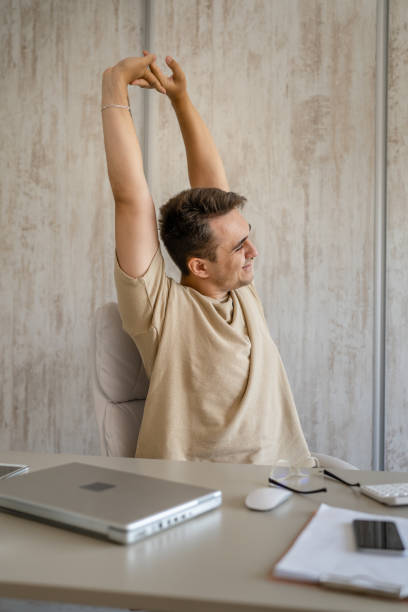 istock young man stretching at work while sitting at desk having back pain 1445862591