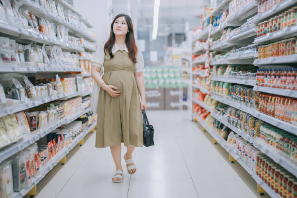 asian chinese pregnant woman buying groceries in supermarket - one person women human pregnancy beautiful imagens e fotografias de stock