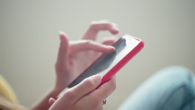 closeup of hands of female internet user with modern smartphone indoors, scrolling and swiping