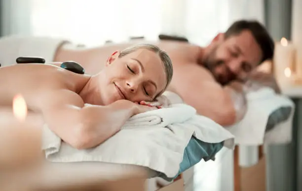 Photo of Relax couple, spa stone back massage and luxury wellness for zen therapy, beauty and rich skincare. Calm, peace and sleeping people on salon bed for healthy stress relief or happy holistic body detox