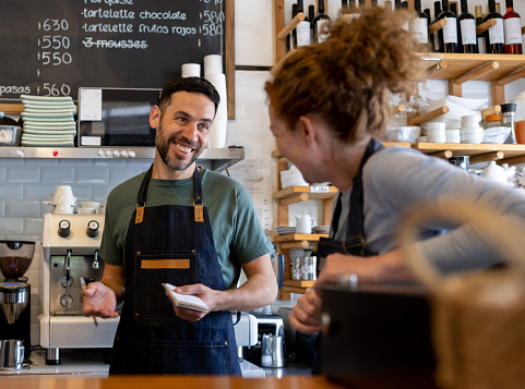 Happy workers at a cafe talking and laughing - small business concepts