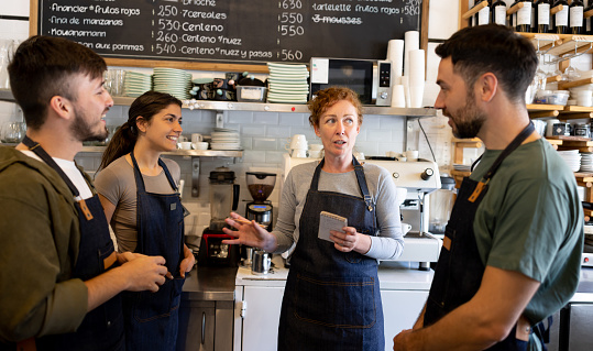 Business owner talking to her staff in a meeting at a cafe - small business concepts