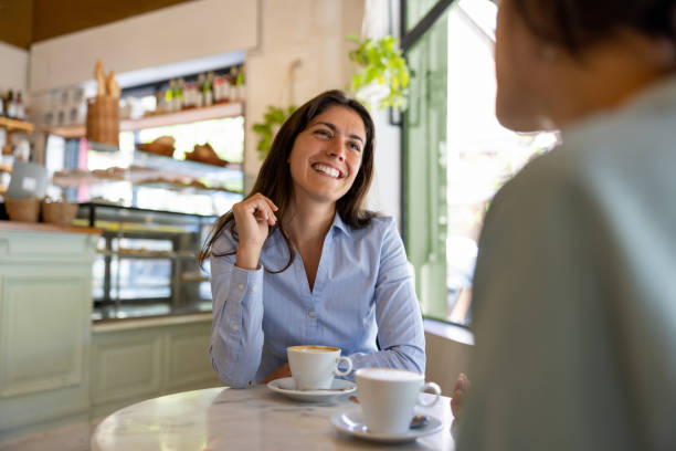 istock Happy women talking while having a cup of coffee at a cafe 1445890937