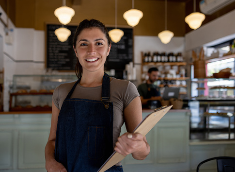 Portrait of a happy waitress working at a cafe and looking at the camera smiling - food service concepts