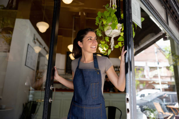 istock Happy waitress opening the doors of a restaurant 1445890996
