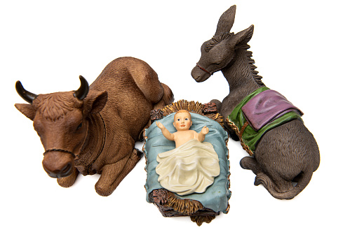 Old figurine Baby Jesus in his crib with ox and donkey from above on white background