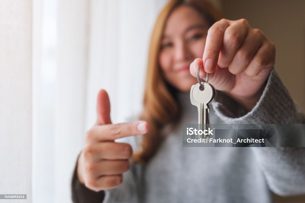 Blurred of a woman holding and pointing finger at the keys for real estate concept Moving House Stock Photo