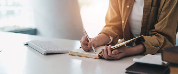 istock Cropped photo of woman writing making list taking notes in notepad working or learning on laptop indoors- educational course or training, seminar, education online concept 1445899317