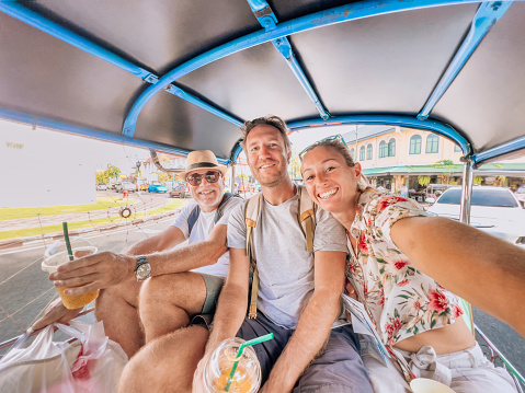 Two generation family traveling together in Thailand.
Three people taking selfie on Tuk Tuk