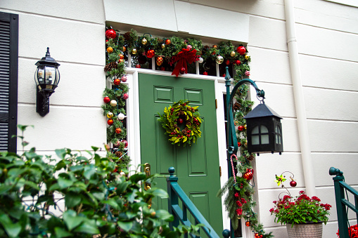 Green front door decorated with a Christmas wreath, garland, and other festive decorations