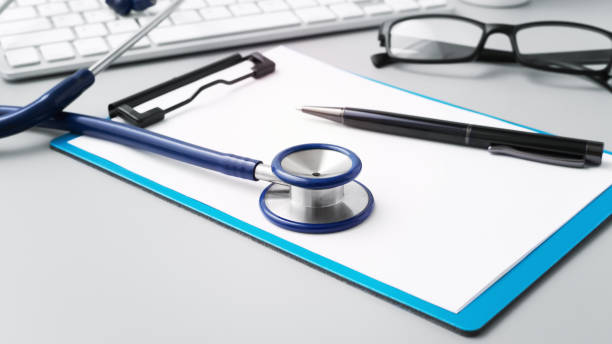 istock Doctor desk with stethoscope on clipboard and pen 1445902426