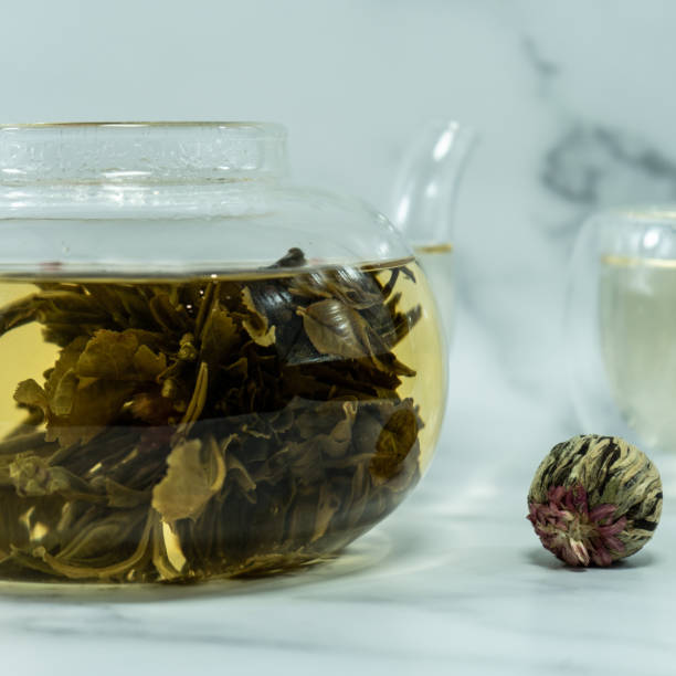 istock Chinese blooming tea. A glass teapot with a blooming tea flower on a white table. 1445904713